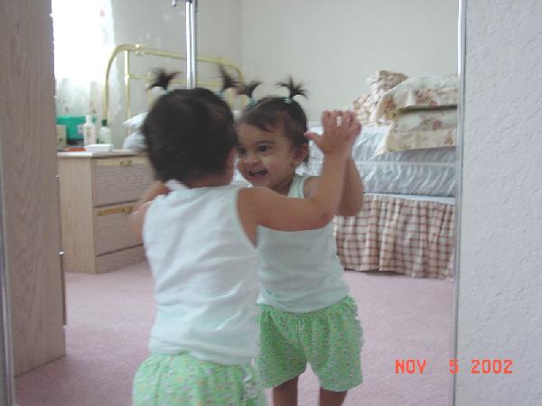 Amira at around 1 year, laughing at her hairdo in the mirror